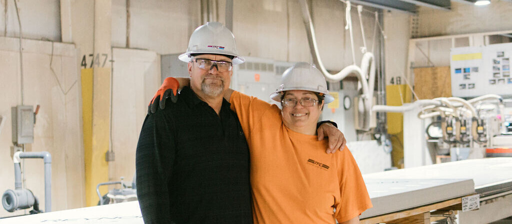 Two TFC employees in the manufacturing shop smiling at the camera.