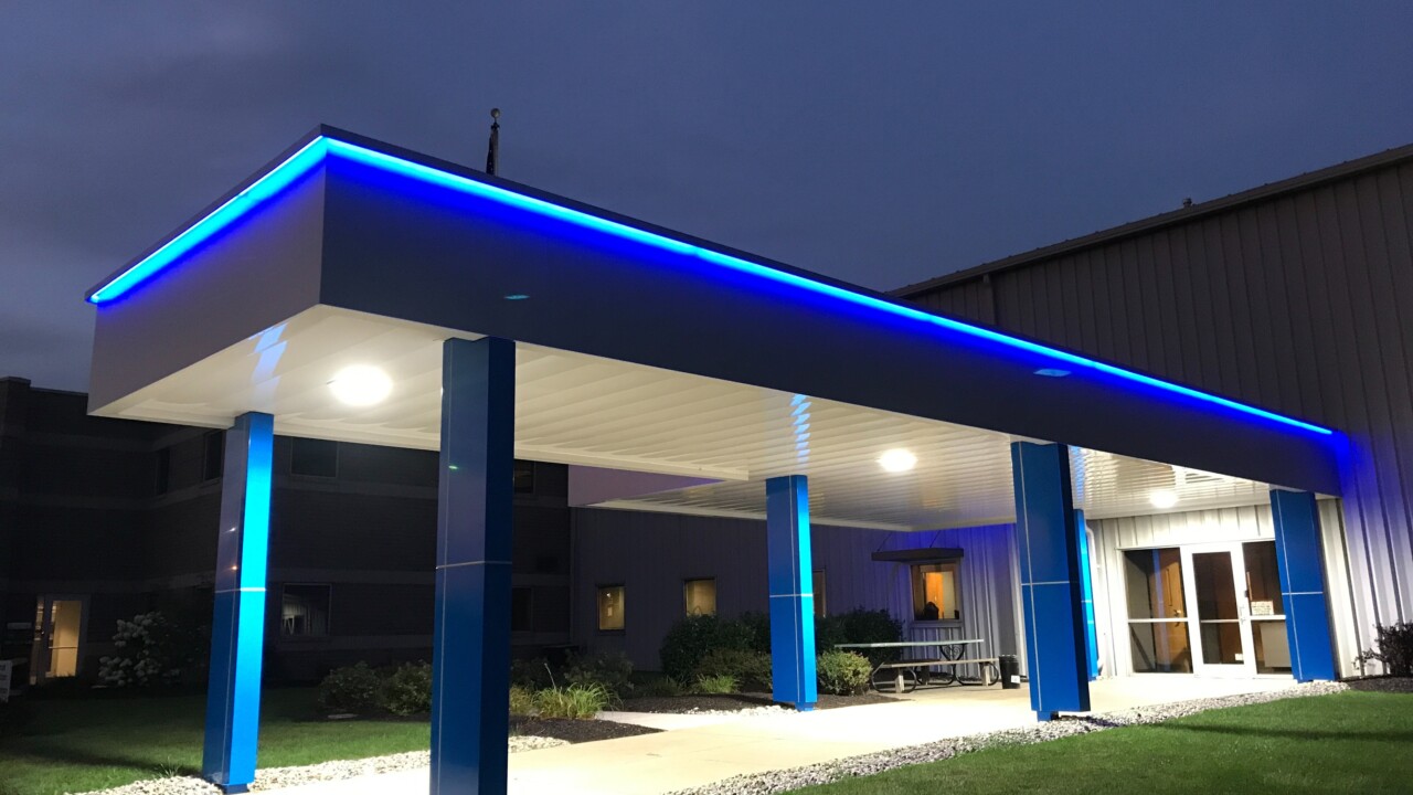 Architectural walkway canopy with bright blue eyebrow lighting.