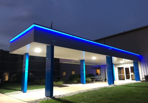 Architectural walkway canopy with bright blue eyebrow lighting.