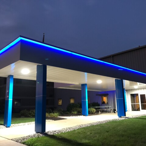 Architectural walkway canopy with bright blue eyebrow lighting.