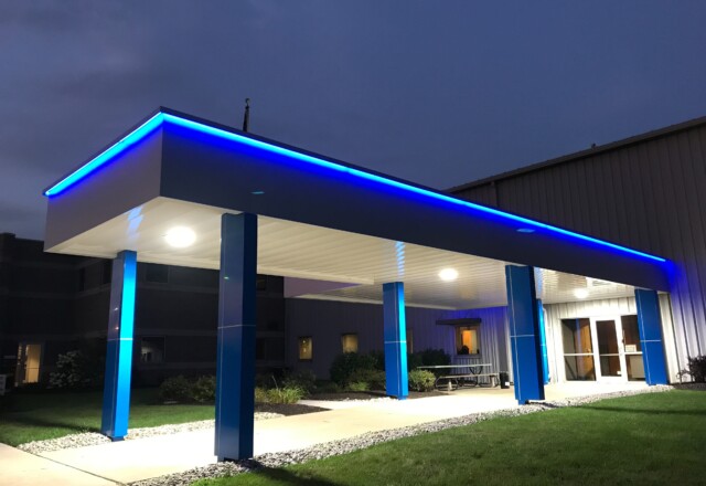 Architectural walkway canopy with bright blue eyebrow lighting.